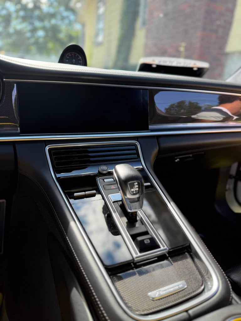 Close-up of a luxury car's interior dashboard and gear shift with chrome trim and black leather